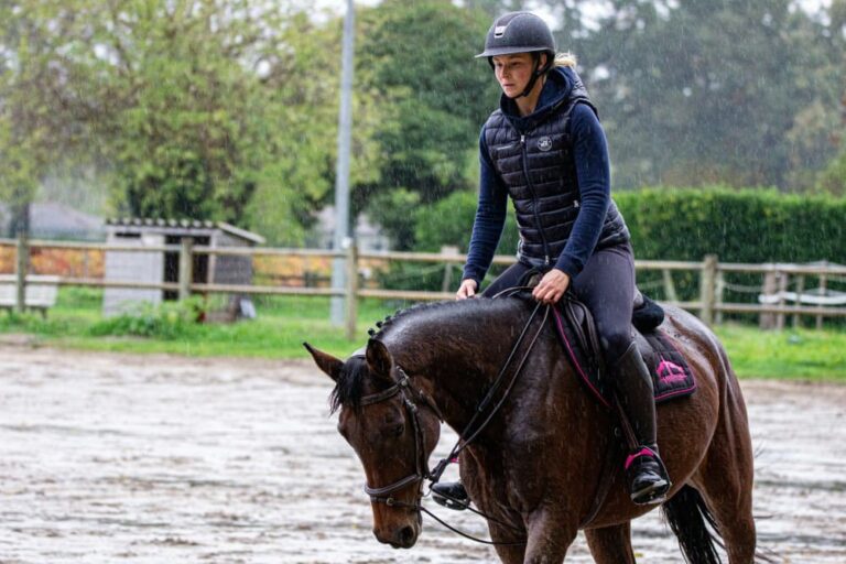 Cavalière sous la pluie mettant son cheval en main galop 4