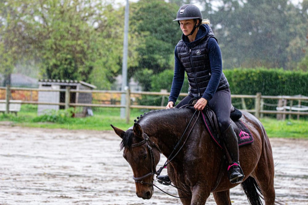 Cavalière sous la pluie mettant son cheval en main galop 4