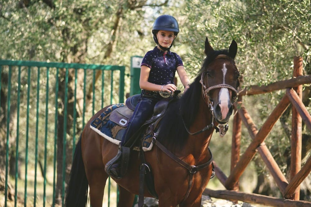 Petite fille qui débute l'équitation sur un grand cheval